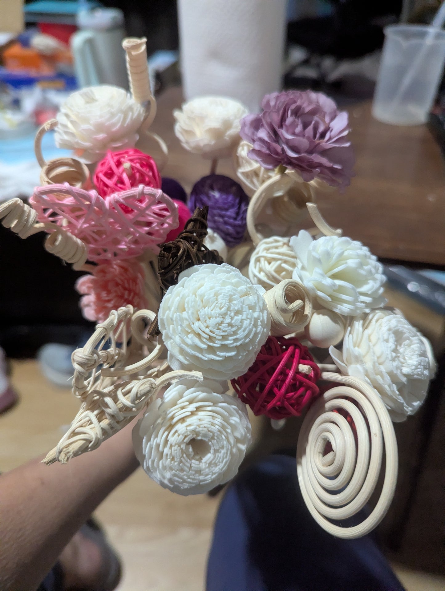 bouquet of decorative paper and reed flowers and spiral reeds, in pinks, purples, creams, and white