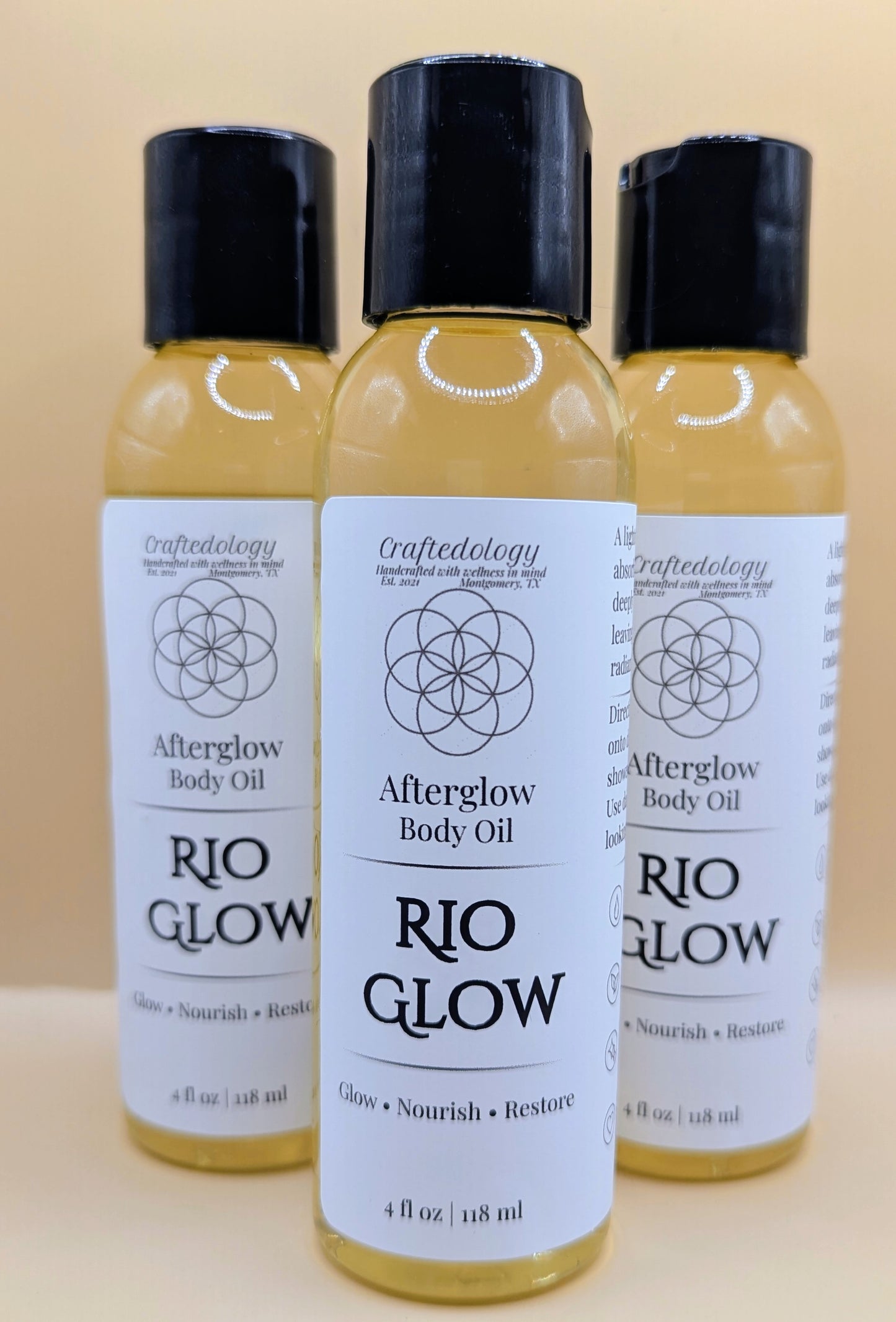 Three bottles of Rio Glow Afterglow Body Oil on a beige background